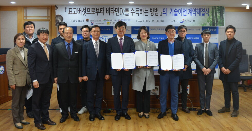 장흥군청  여러 양복을 입은 사람들과  2명의 남자분과 1명의 여자분이 상장을 들며 ㈜천연스토리(대표 김현준)와 연구성과물에 대한 기술이전협약을 체결을 기념하는 단체 사진