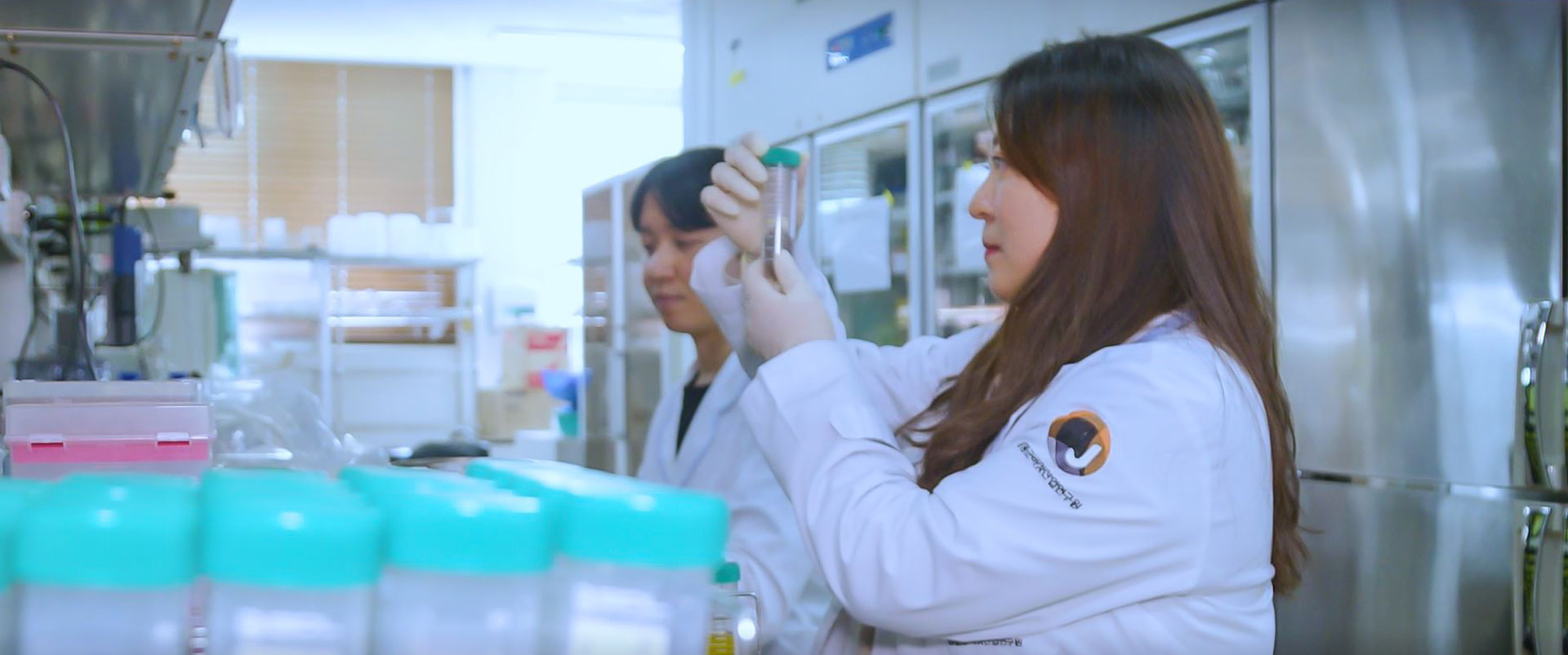 실험실에서 흰색 가운을 입은 여자 연구원이 실험장비의 눈금을 보며 실험을 하는 모습