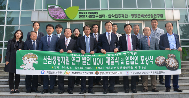산림생명자원 연구발전 mou체결식 및 임업인 포상식현수막을 든 관계자들이 장흥군버섯산업연구원 앞에서 단체기념촬영을 하는 모습