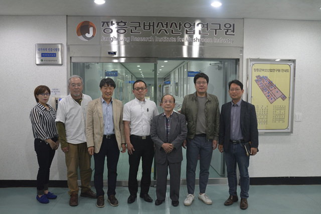장흥군버섯산업연구원 입구에서 설명회에 참석한 관계자들이 나란히 서서 기념촬영을 하고있는 모습