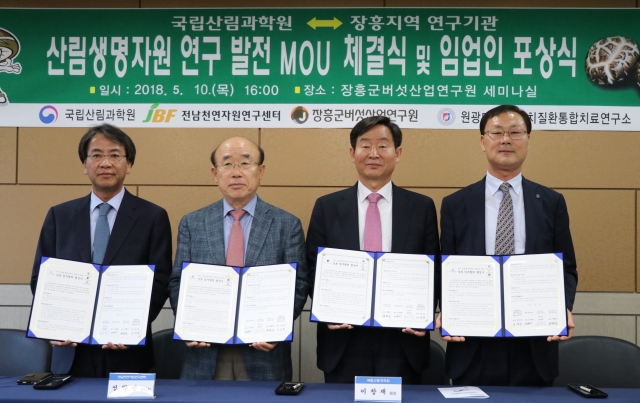 장흥군버섯산업연구원 세미나실에서 국립산림과학원 이창재 원장, 박현 산림생명자원연구부장, 김세현 산림소득자원연구과장, 김만조 산림약용자원연구소장이 나와 업무협약 체결장을 손에 들고 산림생명자원 연구 발전 MOU 체결식 및 임업인 포상식을 기념하는 모습을 담은 사진