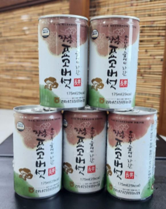 아래에는 장흥표고버섯음료 3캔과 3캔위에는 2캔의 장흥표고버섯 음료캔이 올라와져 있는 모습을 담은 사진