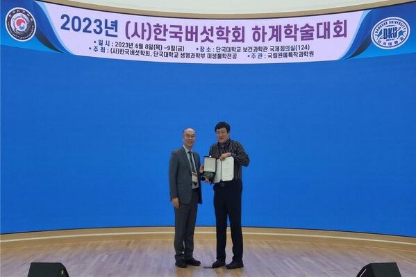 한국버섯학회 하계학술대회에서 학술상을 수상하여 2명의 남자가 무대에 올라가 수상식을 하는 모습을 담은 사진