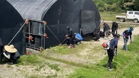 2명의 남자가 예초작업과 뒤에는 여러 사람들이 앉아서 잡목관리, 주병 환경정비등을 하는 모습을 담은 사진